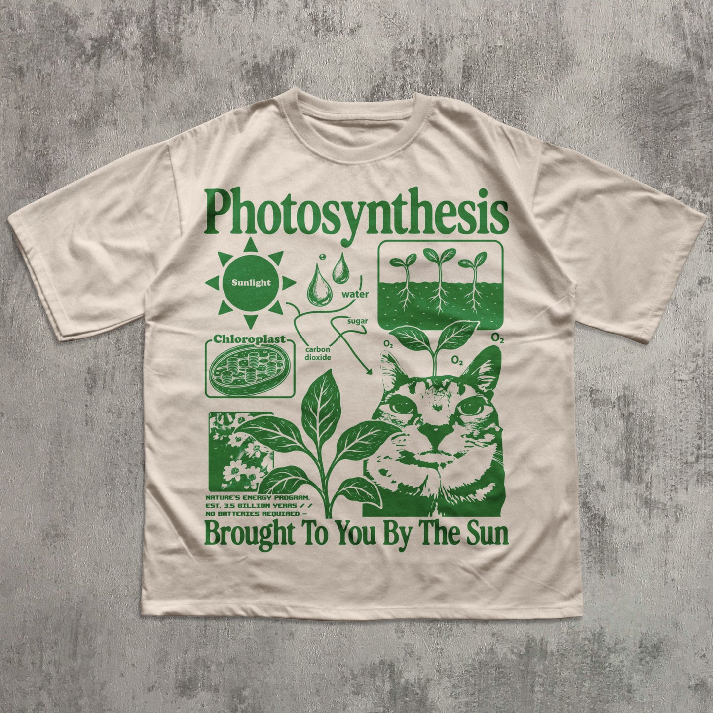 A beige short-sleeve t-shirt with a green graphic print titled 'Photosynthesis' featuring a cat illustration and educational diagrams, laid flat on a textured gray background.