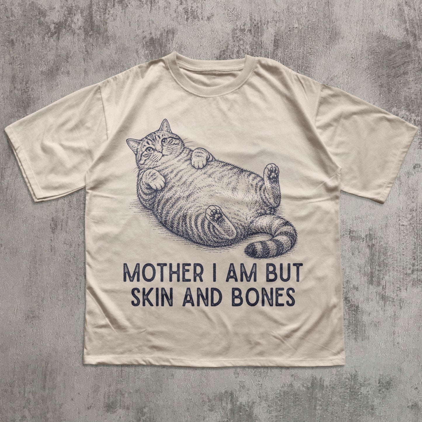 Beige t-shirt with a cat illustration and text on a textured gray background