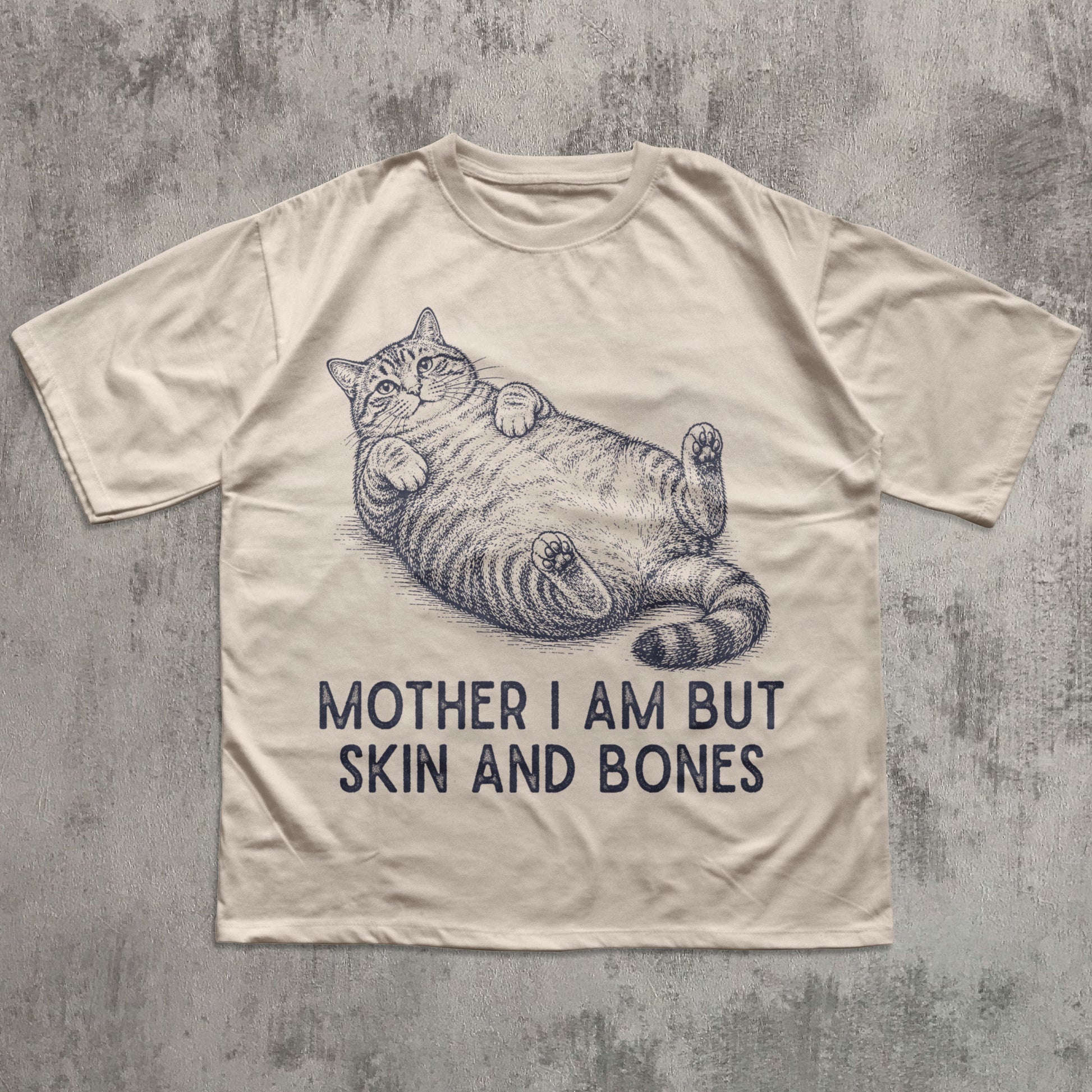Beige t-shirt with a cat illustration and text on a textured gray background