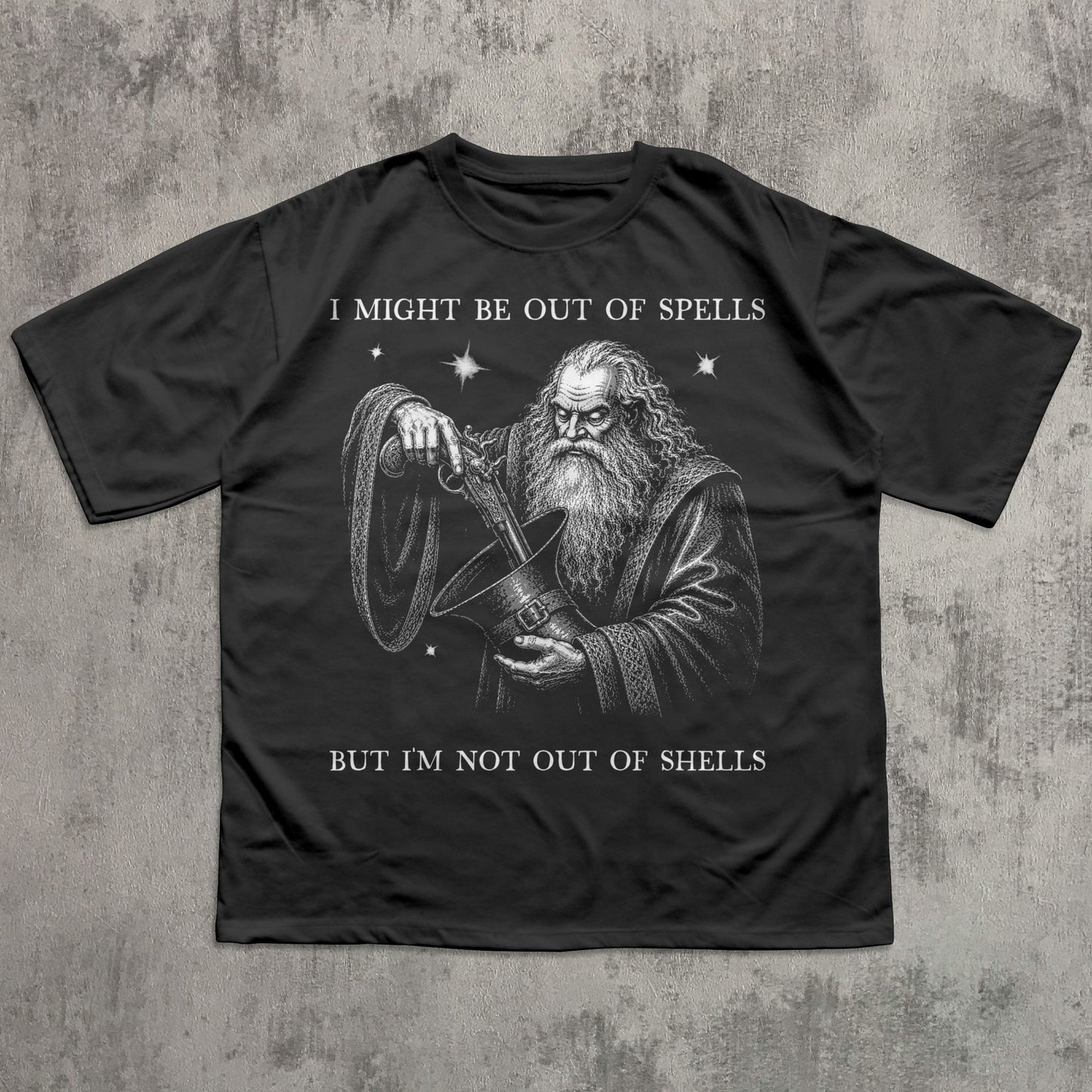 A black short-sleeve t-shirt with a white graphic print of a wizard holding a shell, with the text 'I MIGHT BE OUT OF SPELLS BUT I'M NOT OUT OF SHELLS' on a textured gray background.