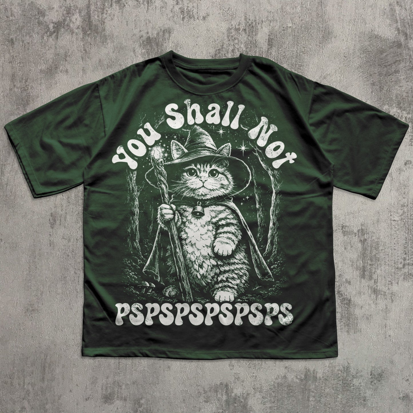 Green t-shirt with a cat in a wizard costume graphic and text on a concrete surface