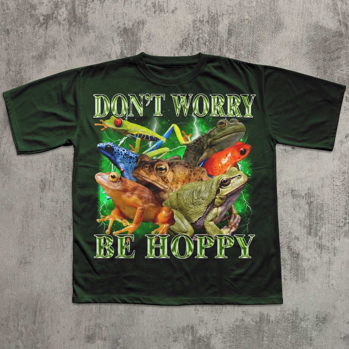 Green t-shirt with colorful frogs and text 'Don't Worry Be Hoppy' on a textured gray background