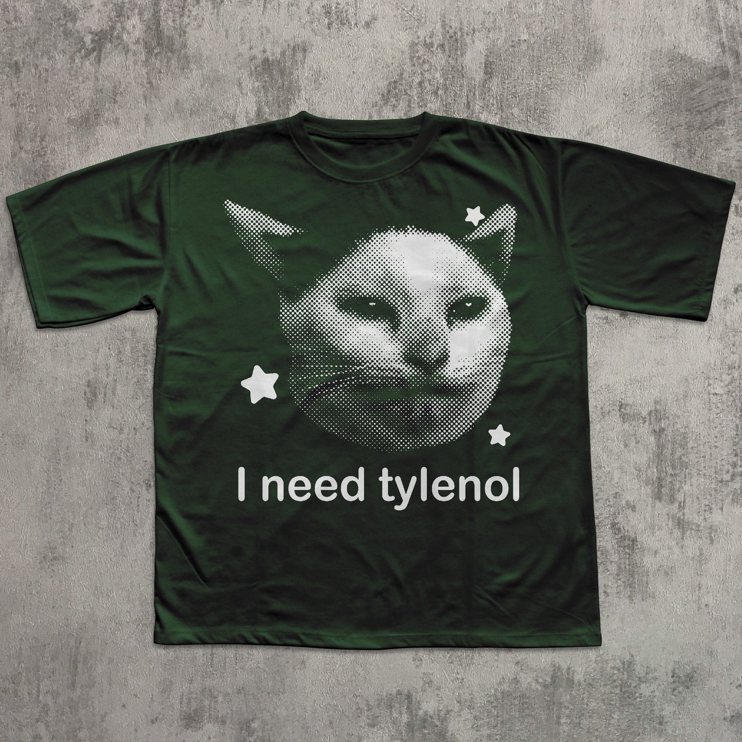 Green t-shirt with a cat graphic and 'I need tylenol' text on a textured gray background