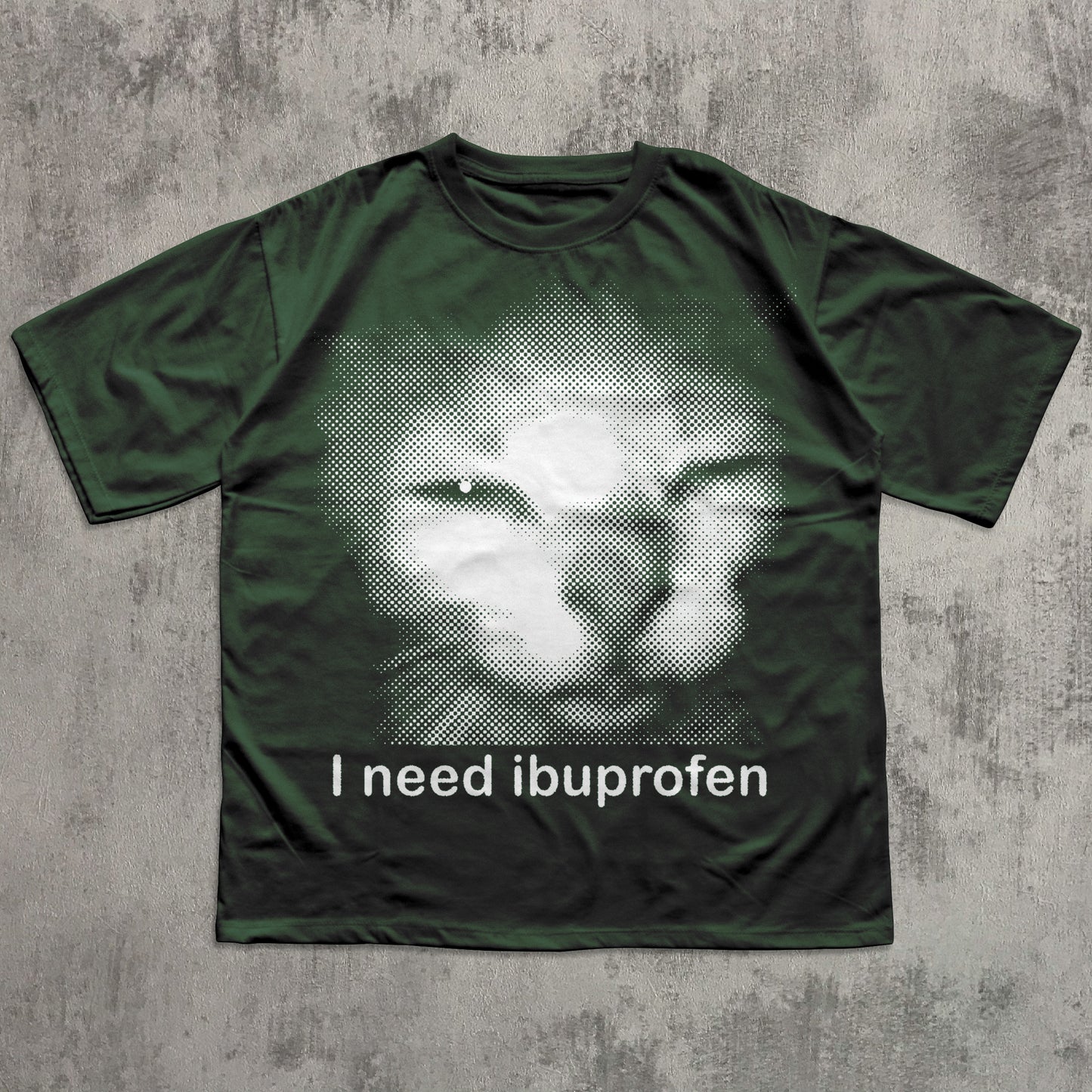 Green t-shirt with a graphic of a cat and text 'I need ibuprofen' on a textured gray background