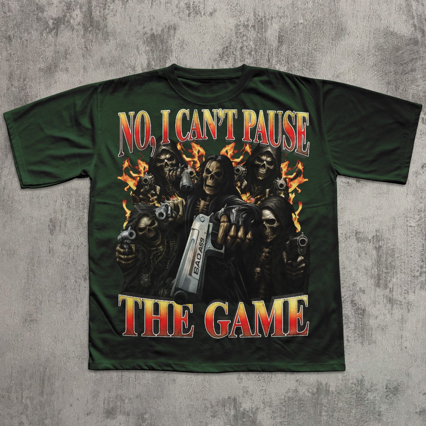 Green t-shirt with graphic design of skeletons holding guns and a pause button, text 'No, I Can't Pause The Game' on a textured gray background.