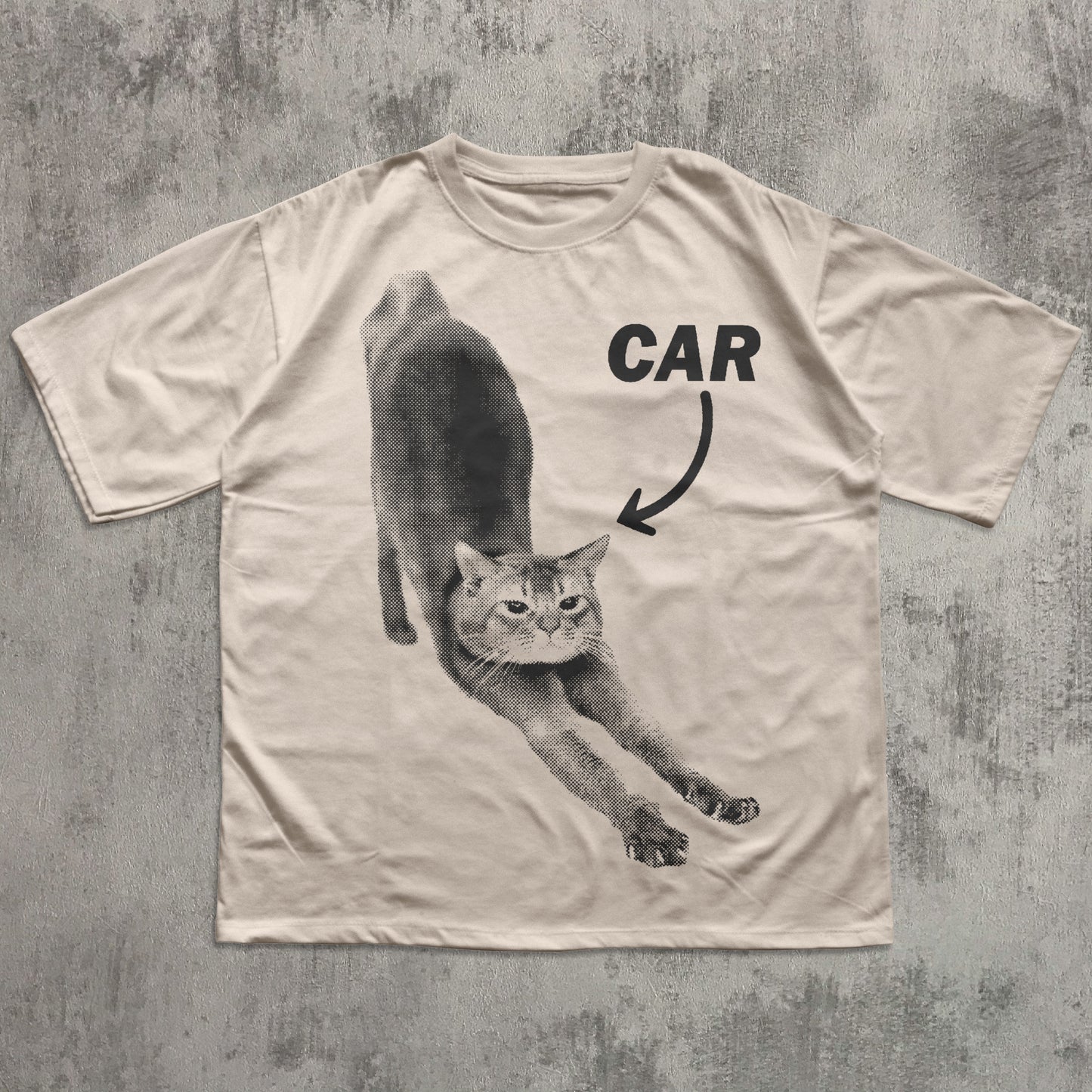 Beige t-shirt with a graphic of a cat and the word 'CAR' on a textured gray background