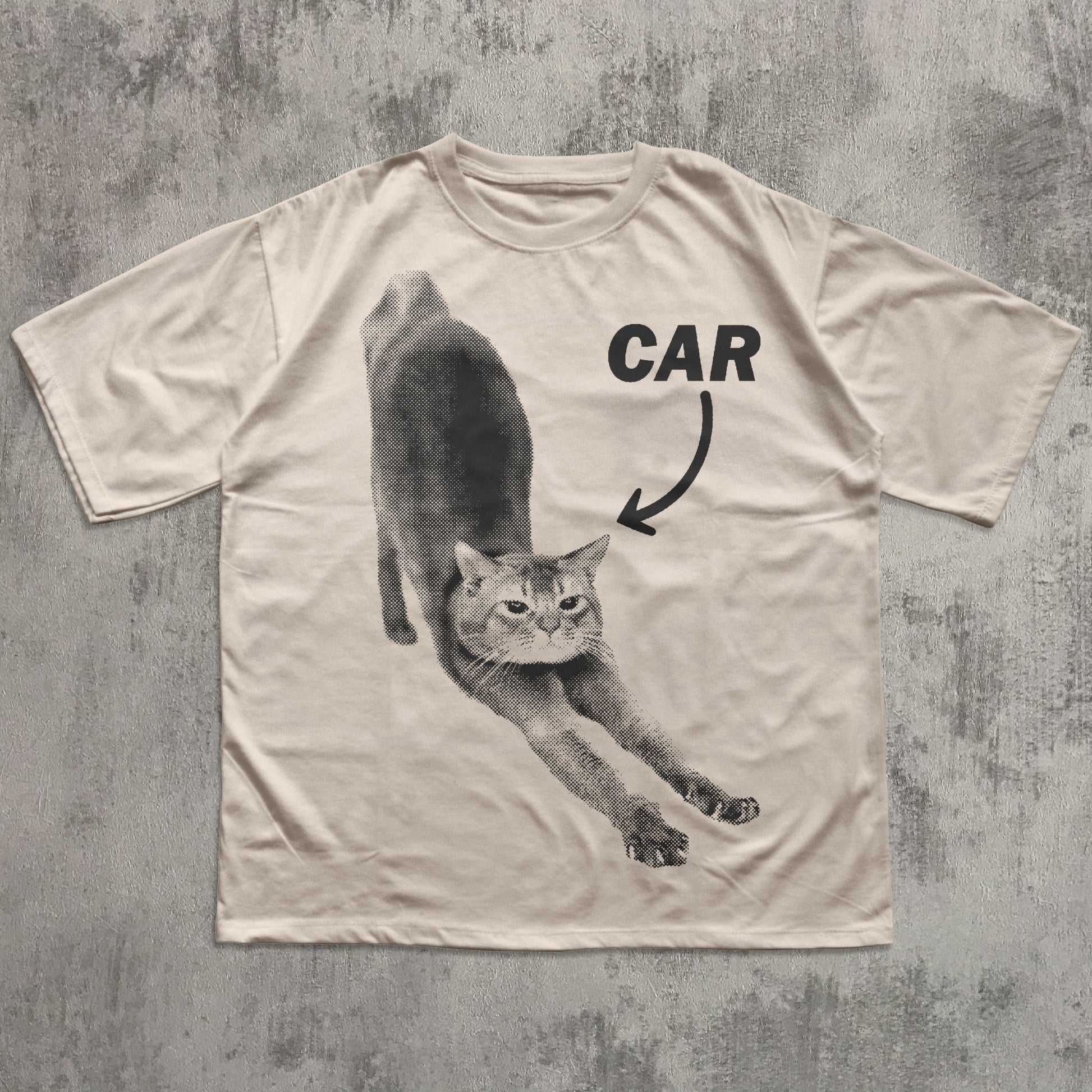 Beige t-shirt with a graphic of a cat and the word 'CAR' on a textured gray background