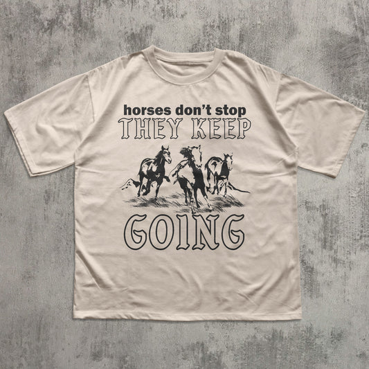 Beige t-shirt with graphic horse design and text on a textured gray background