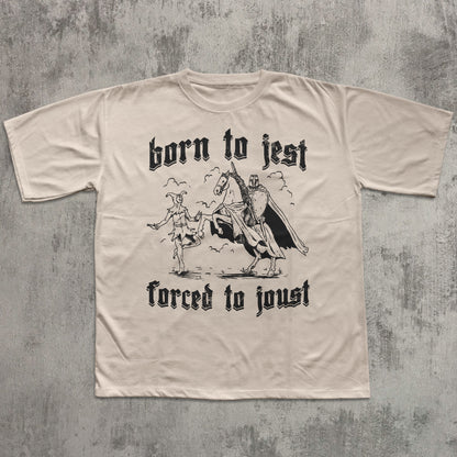 Beige t-shirt with black graphic and text 'born to jest, forced to joust' on a textured gray background