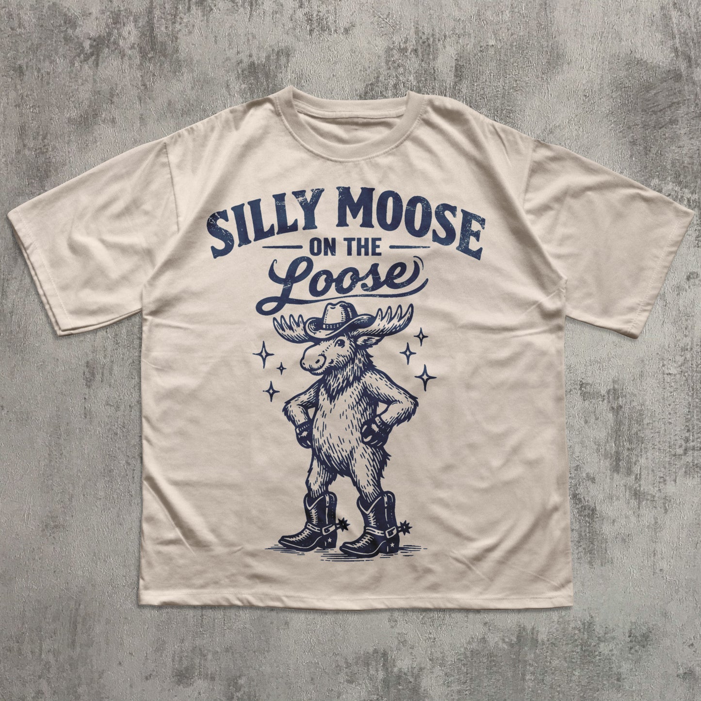 Beige t-shirt with 'Silly Moose on the Loose' graphic and text on a textured gray background