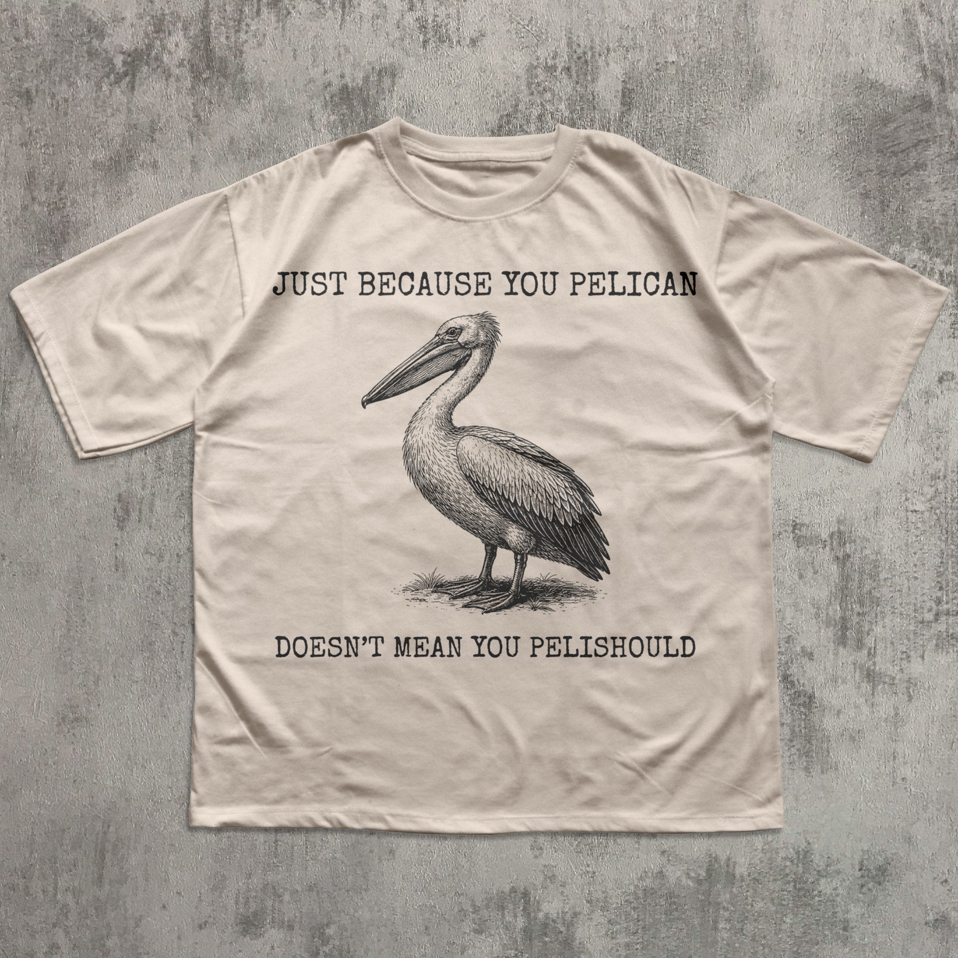 Beige t-shirt with a pelican graphic and humorous text on a textured gray background