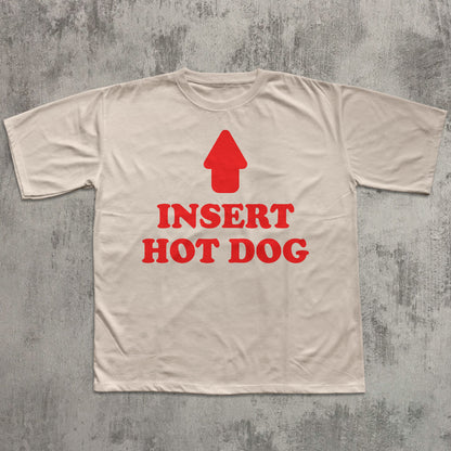 Beige t-shirt with red graphic and text 'Insert Hot Dog' on a textured gray background