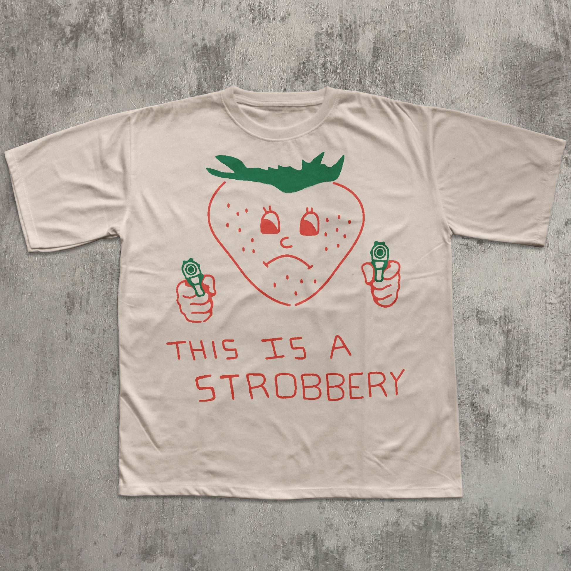 Beige t-shirt with a strawberry graphic and text on a textured gray background