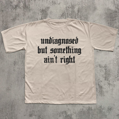 Beige t-shirt with black text on a textured gray background