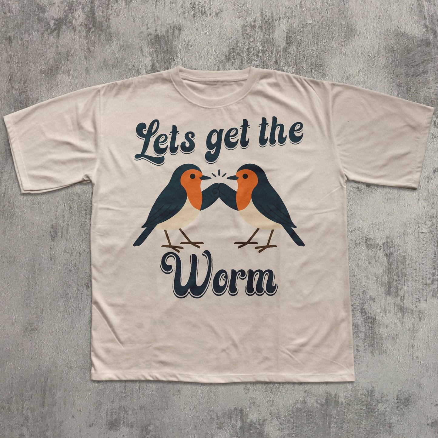 Beige t-shirt with birds graphic and text 'Let's get the Worm' on a textured gray background