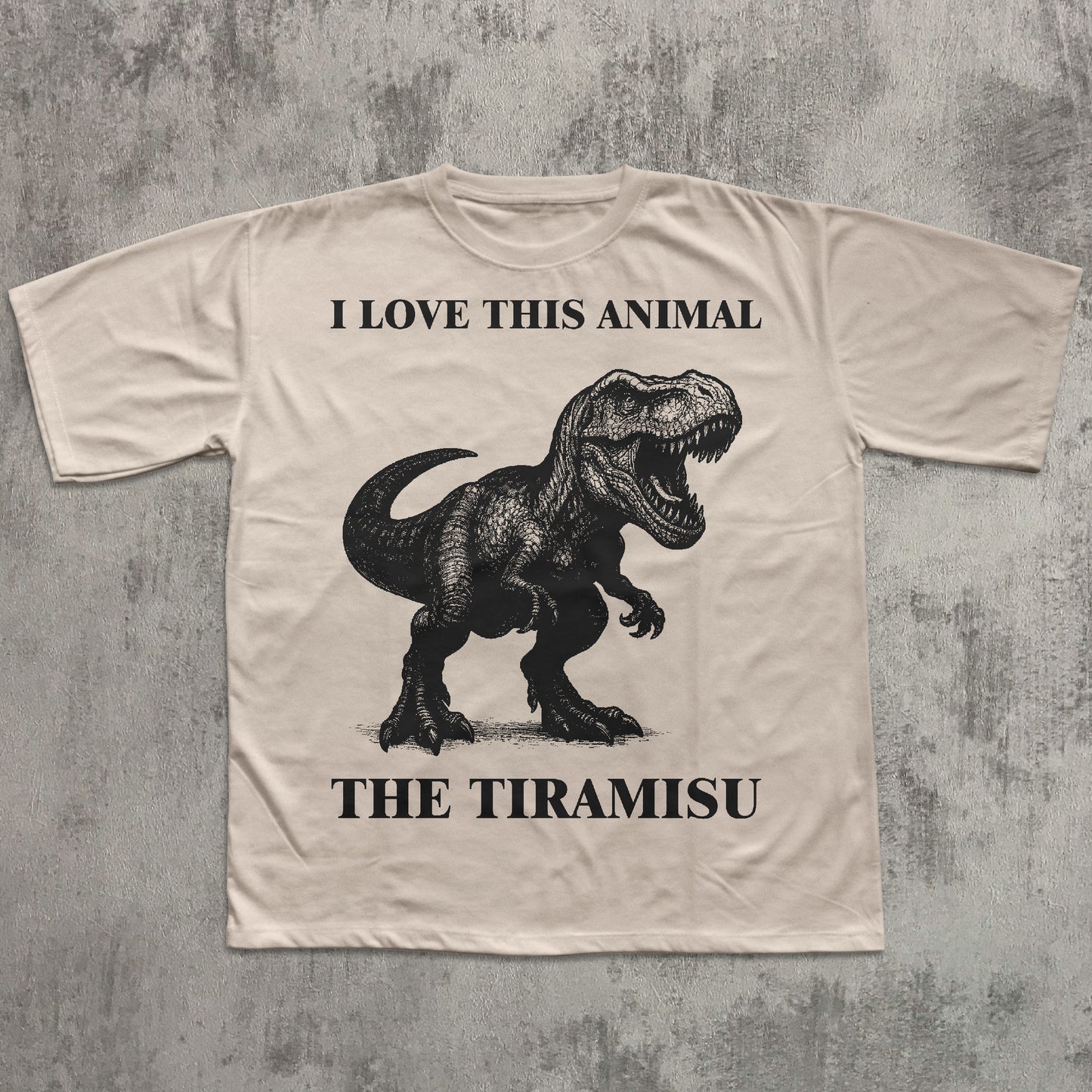 Beige t-shirt with a dinosaur graphic and text on a textured gray background
