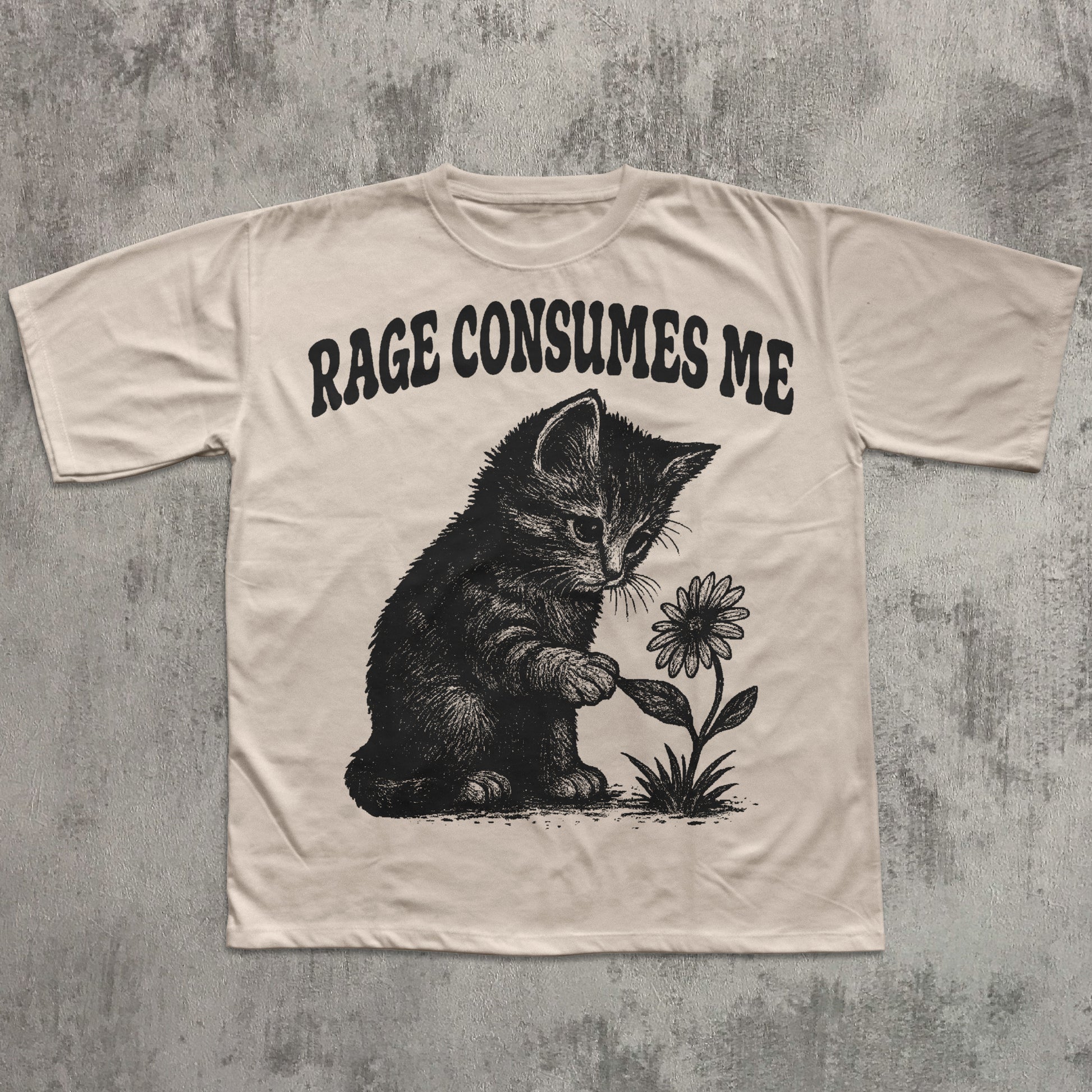 Beige t-shirt with a graphic of a kitten holding a flower and text 'RAGE CONSUMES ME' on a textured gray background.