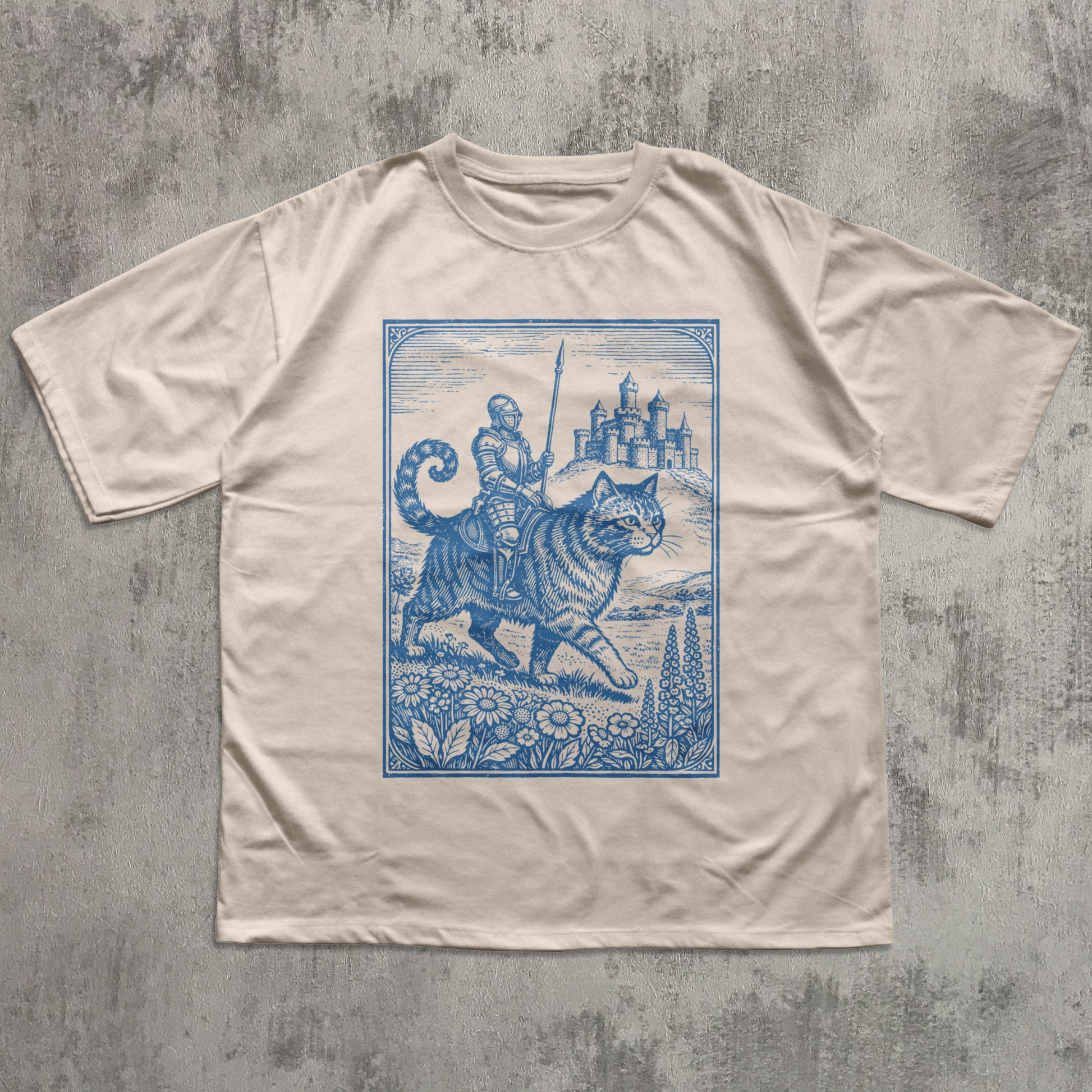 Beige t-shirt with blue graphic of a cat and warrior on a textured gray background