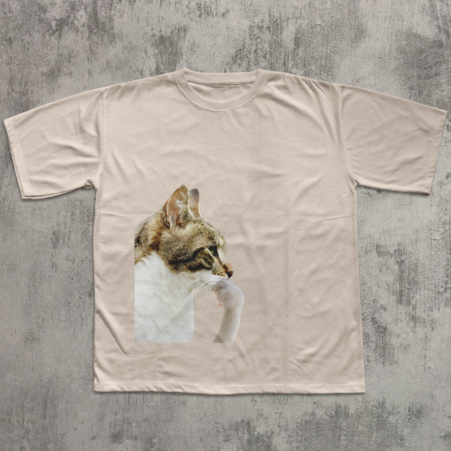 Beige t-shirt with a cat graphic on a textured gray background
