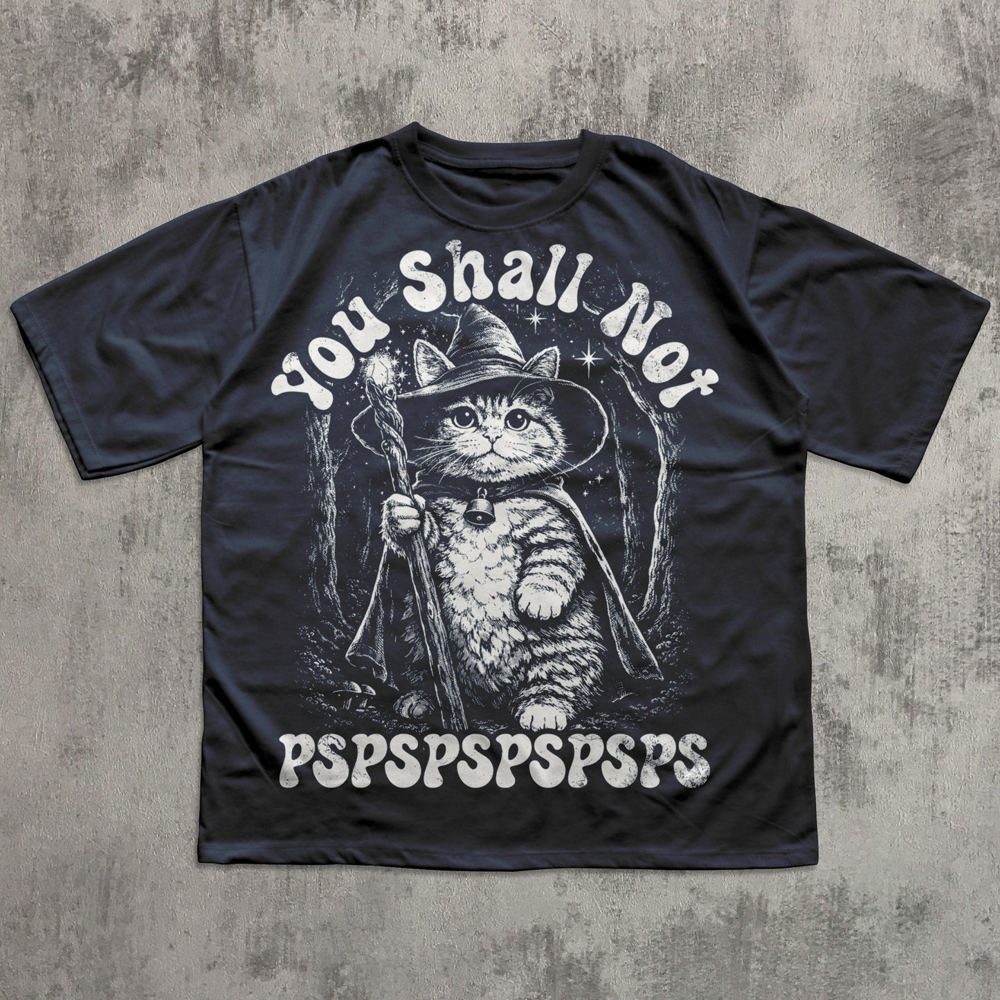 Black t-shirt with a cat in a wizard hat graphic and text on a concrete background