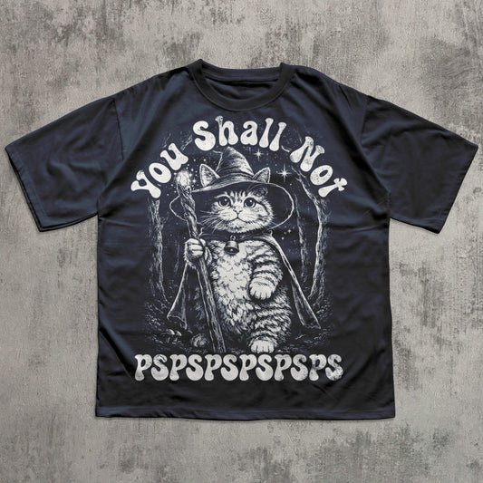 Black t-shirt with a cat in a wizard hat graphic and text on a concrete background