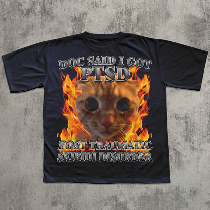 Black t-shirt with a cat graphic and text on a concrete surface