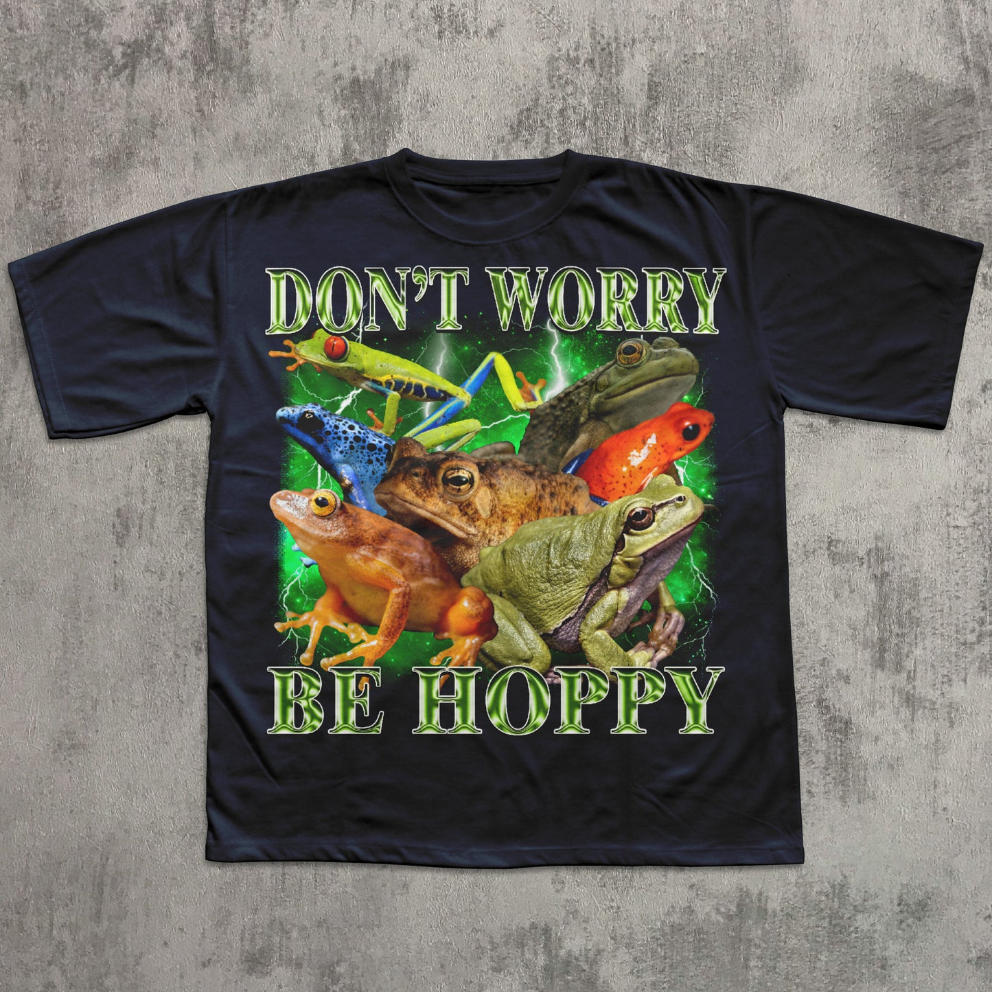 Black t-shirt with colorful frog design and text 'Don't Worry Be Hoppy' on a textured gray background