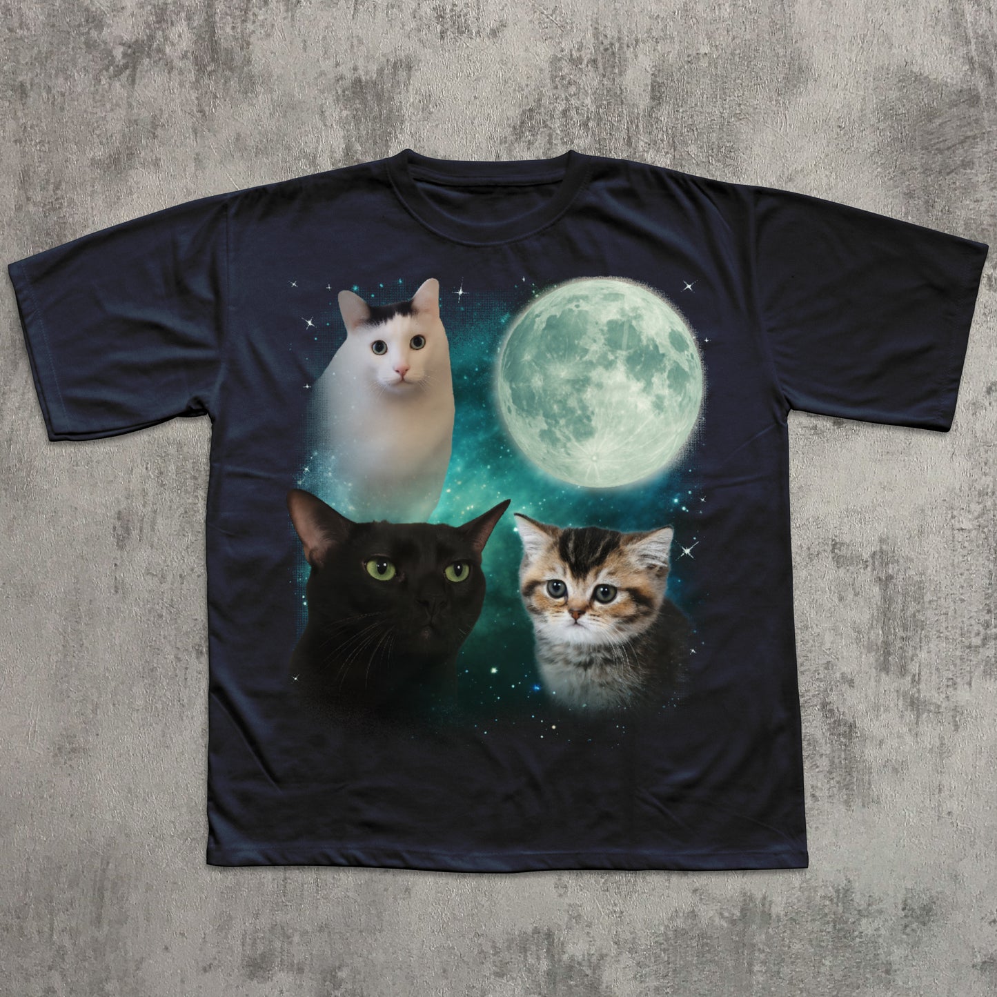 Black t-shirt with cats and a moon graphic on a textured gray surface