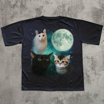 Black t-shirt with cats and a moon graphic on a textured gray surface