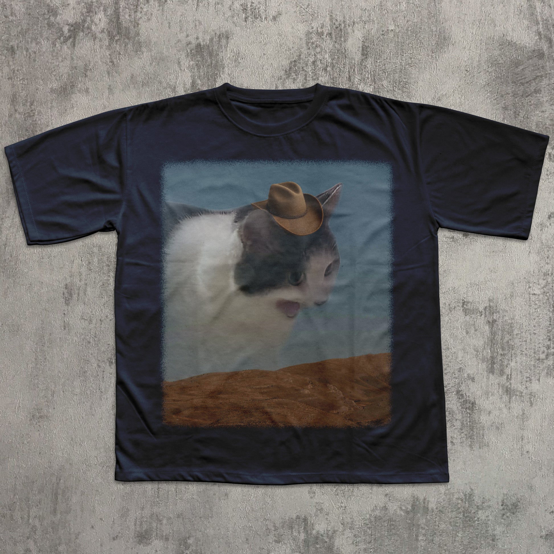 Black t-shirt with a printed design of a cat wearing a cowboy hat on a textured gray background