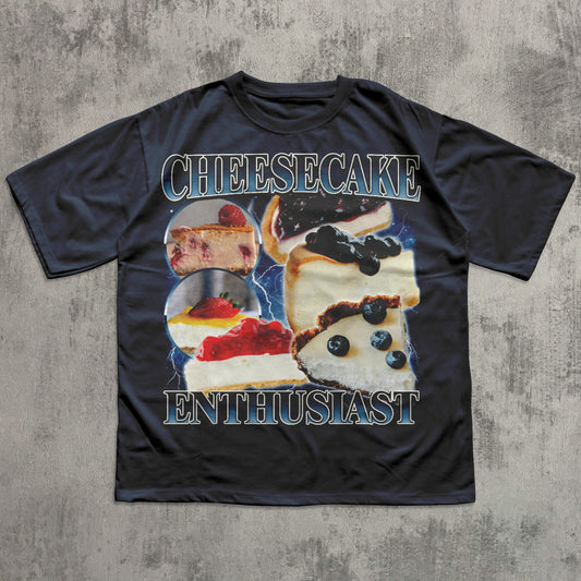 Black t-shirt with cheesecake graphic and text on a textured gray background