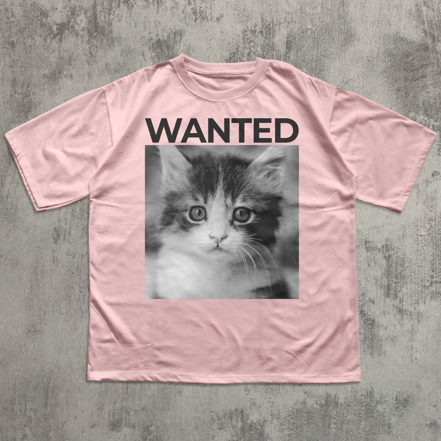 Pink t-shirt with a kitten photo and 'WANTED' text on a textured gray background