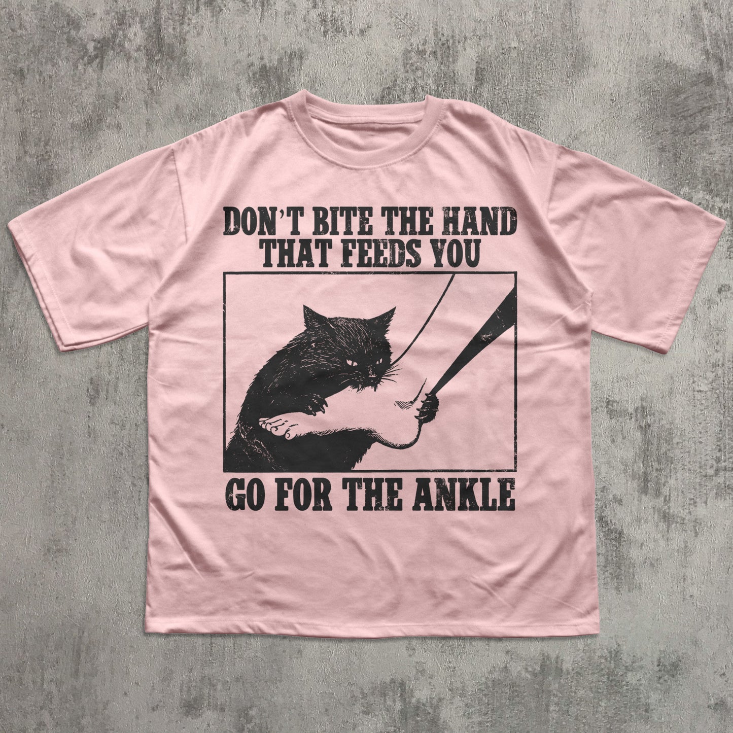 Pink t-shirt with black graphic and text on a textured gray background