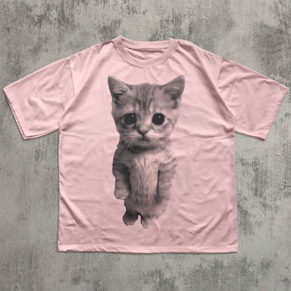 Pink t-shirt with a black and white kitten graphic on a textured gray background