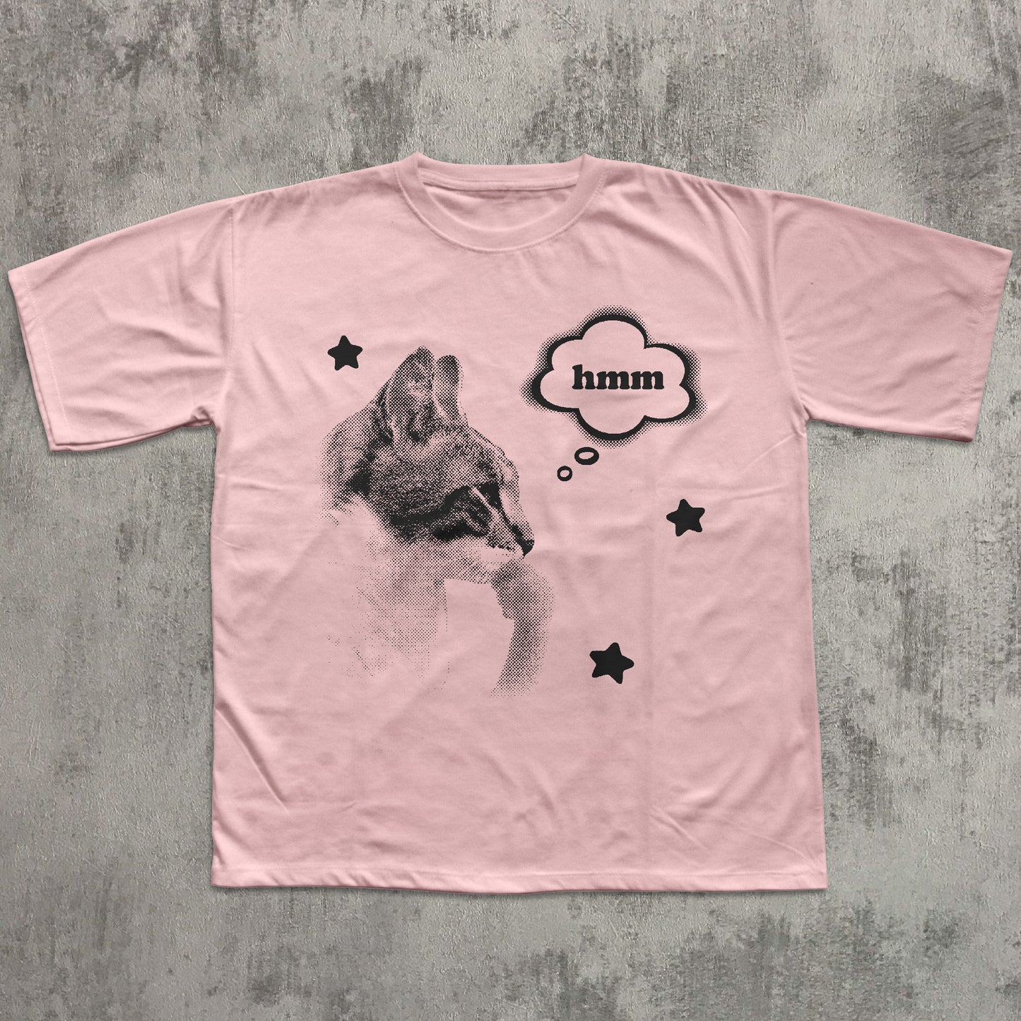Pink t-shirt with a graphic of a cat and 'hmm' text on a textured gray background