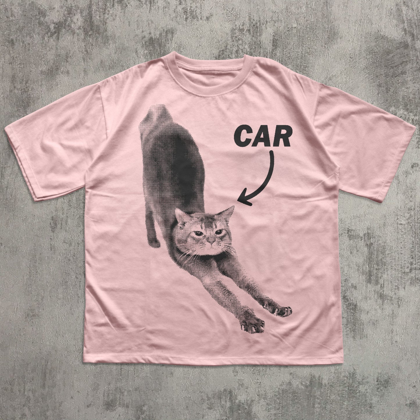 Pink t-shirt with a graphic of a cat and the word 'CAR' on a textured gray background
