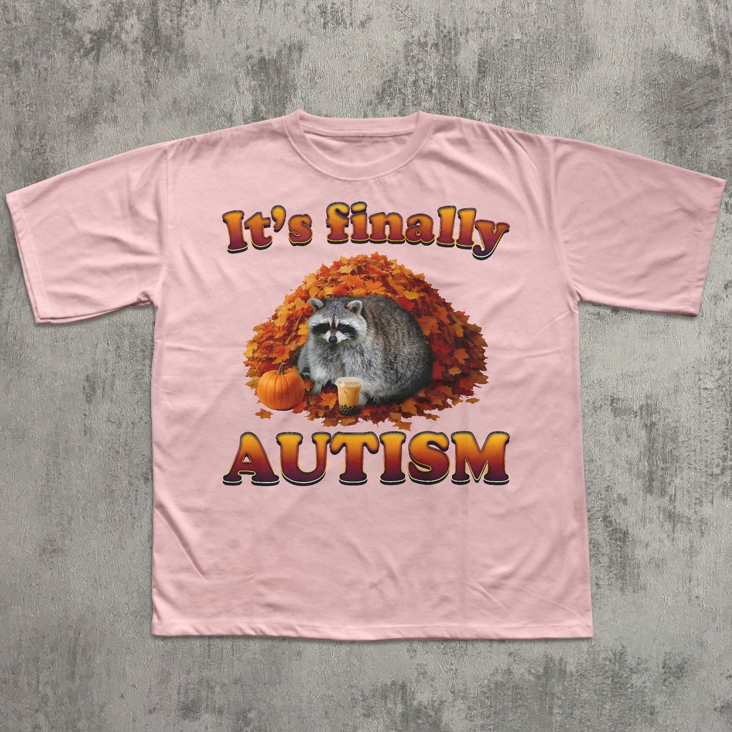 Pink t-shirt with raccoon graphic and text 'It's finally AUTISM' on a textured gray background