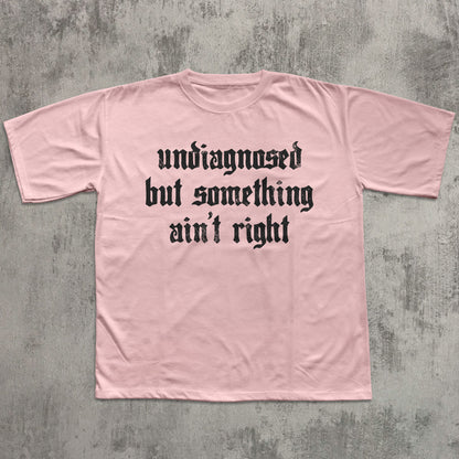 Pink t-shirt with black text on a gray concrete background