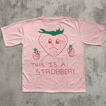 Pink t-shirt with a strawberry graphic and text on a gray concrete background
