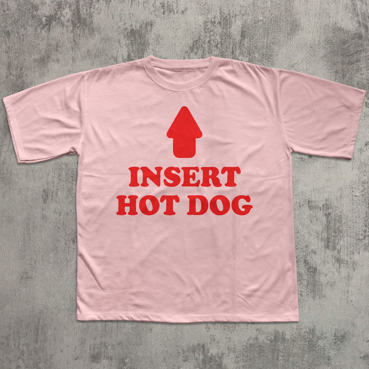 Pink t-shirt with red graphic and text 'Insert Hot Dog' on a gray textured background