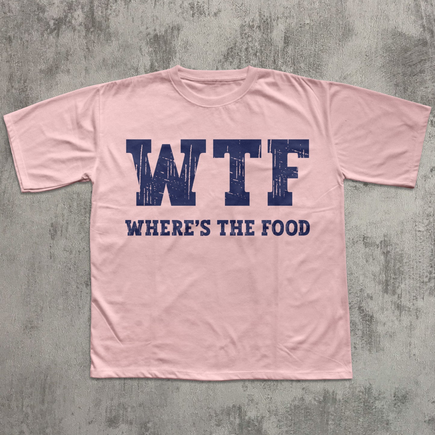 Pink t-shirt with 'WTF WHERE'S THE FOOD' text on a gray concrete background