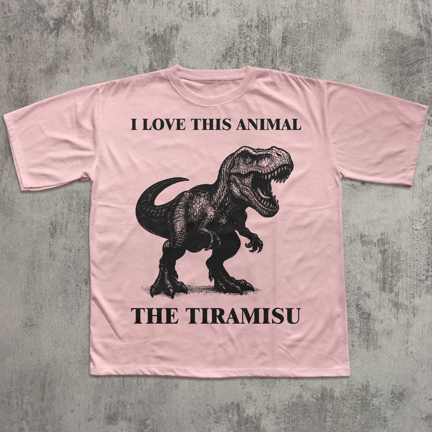 Pink t-shirt with a dinosaur graphic and text on a concrete surface