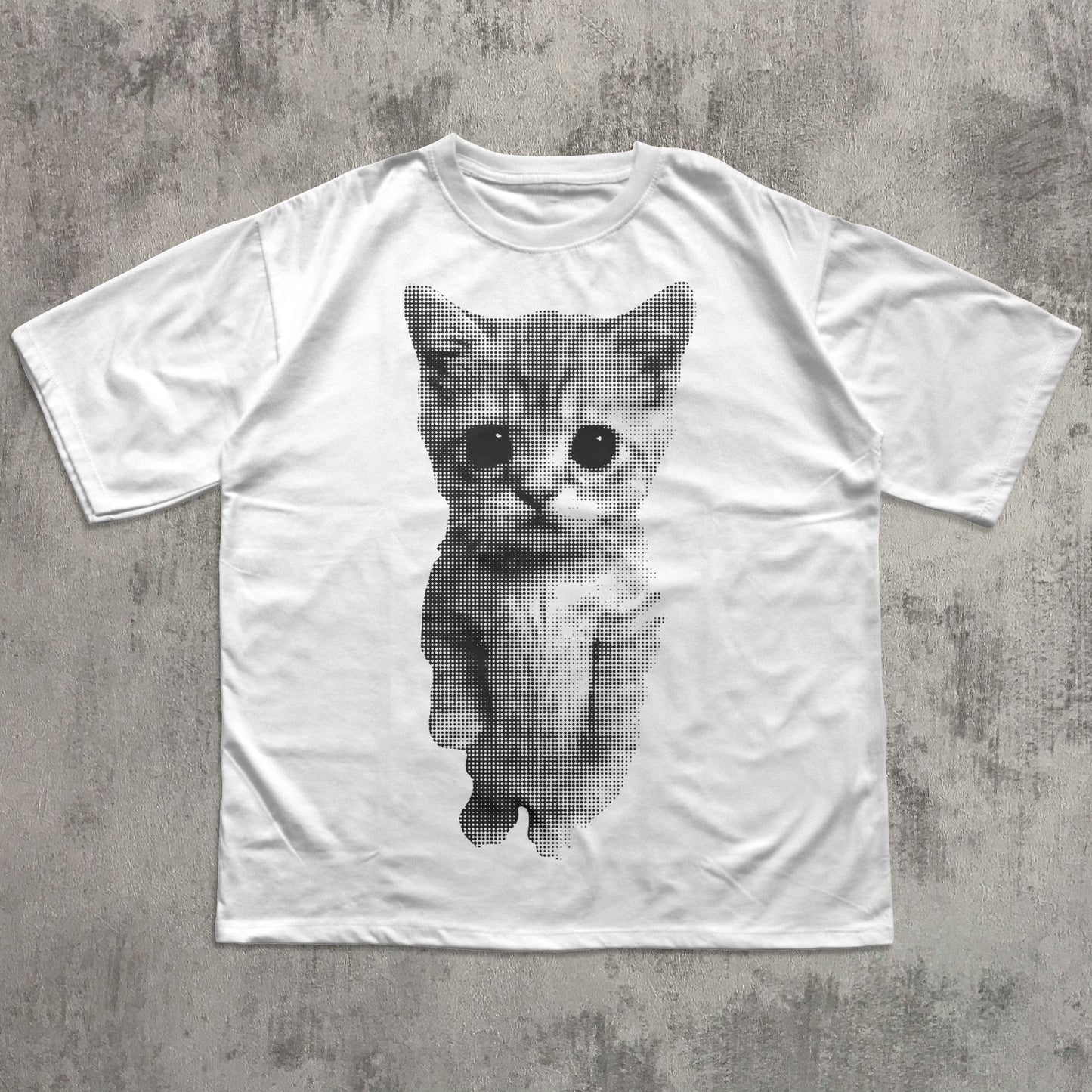 White t-shirt with a printed cat design on a concrete surface