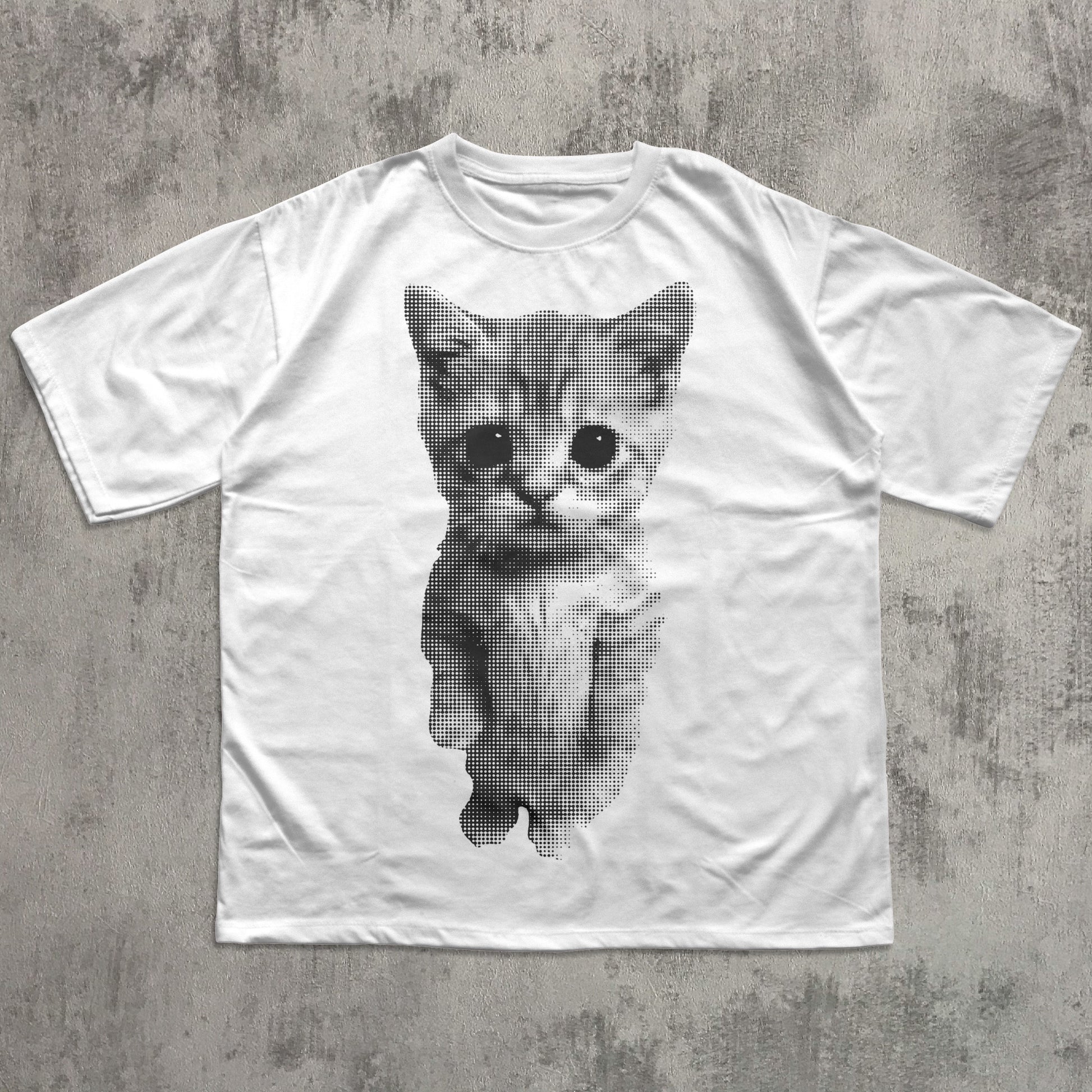 White t-shirt with a printed cat design on a concrete surface