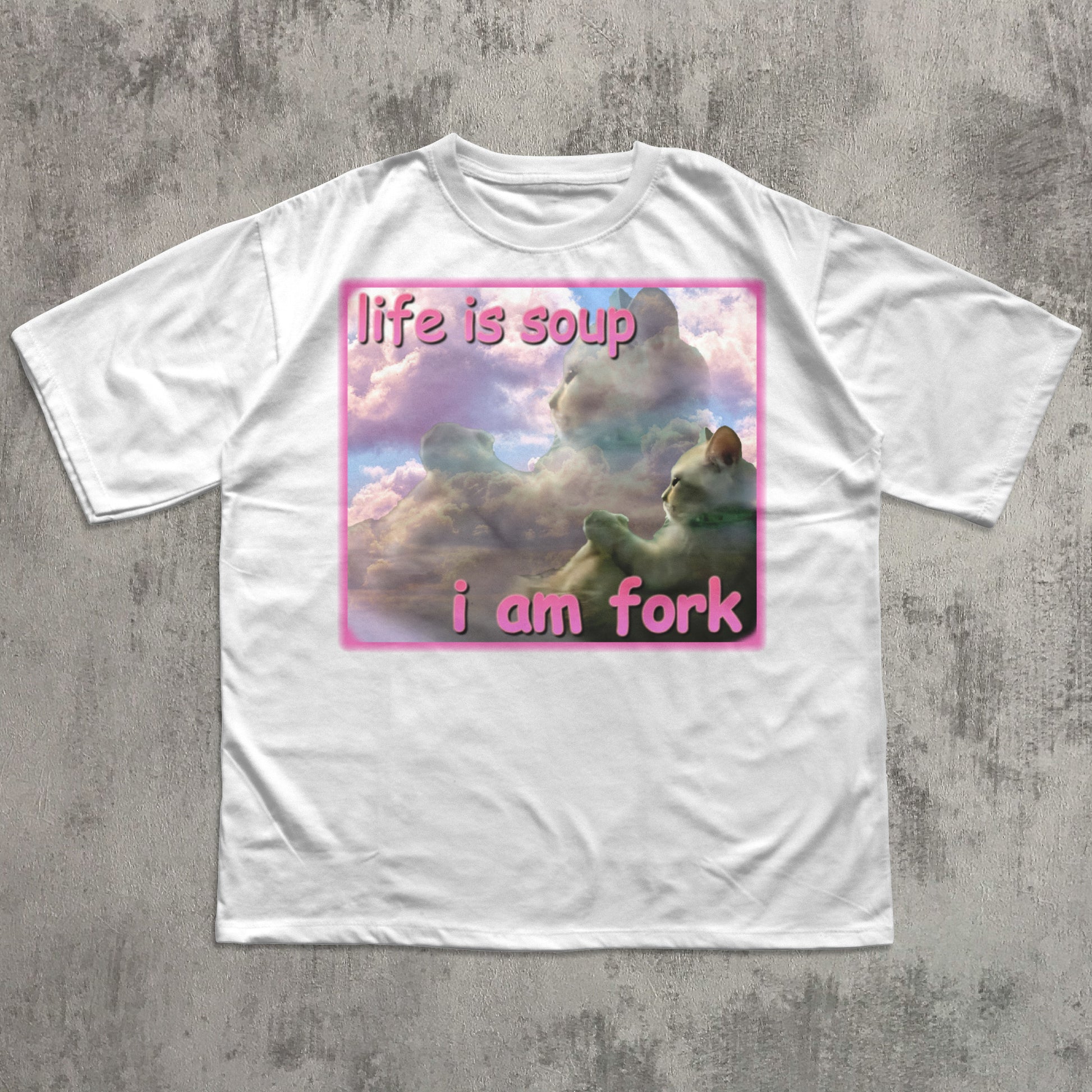 White t-shirt with a graphic design featuring cats and text on a concrete surface