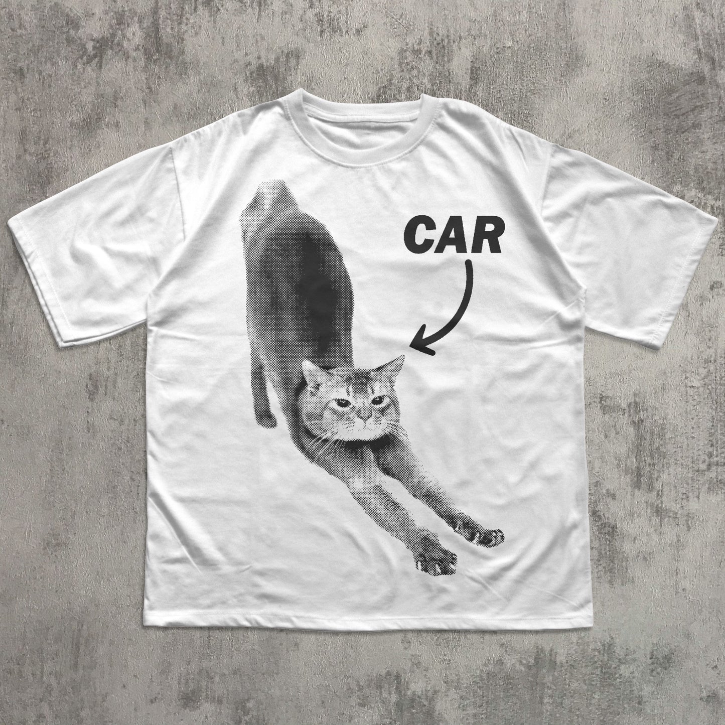 White t-shirt with a graphic of a cat and the word 'CAR' on a concrete surface