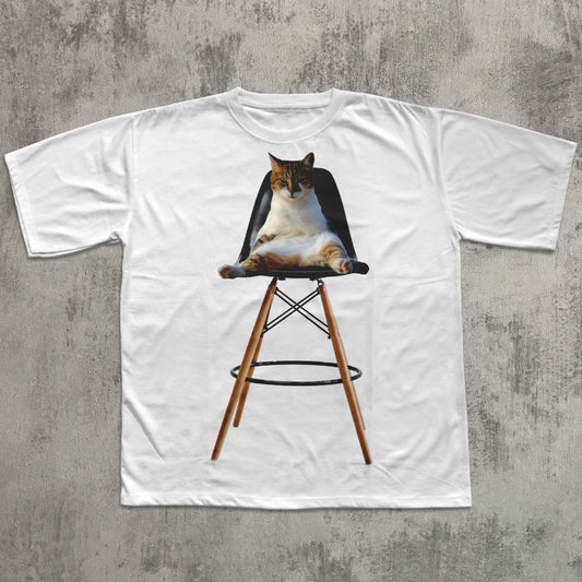 White t-shirt with a graphic of a cat on a chair against a concrete wall background