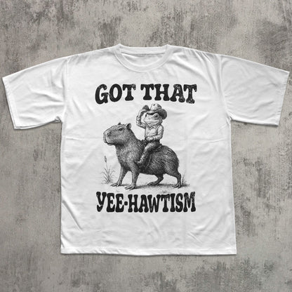 White t-shirt with graphic design of a person riding a capybara and text on a concrete background