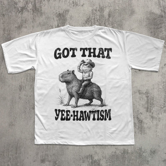 White t-shirt with graphic design of a person riding a capybara and text on a concrete background