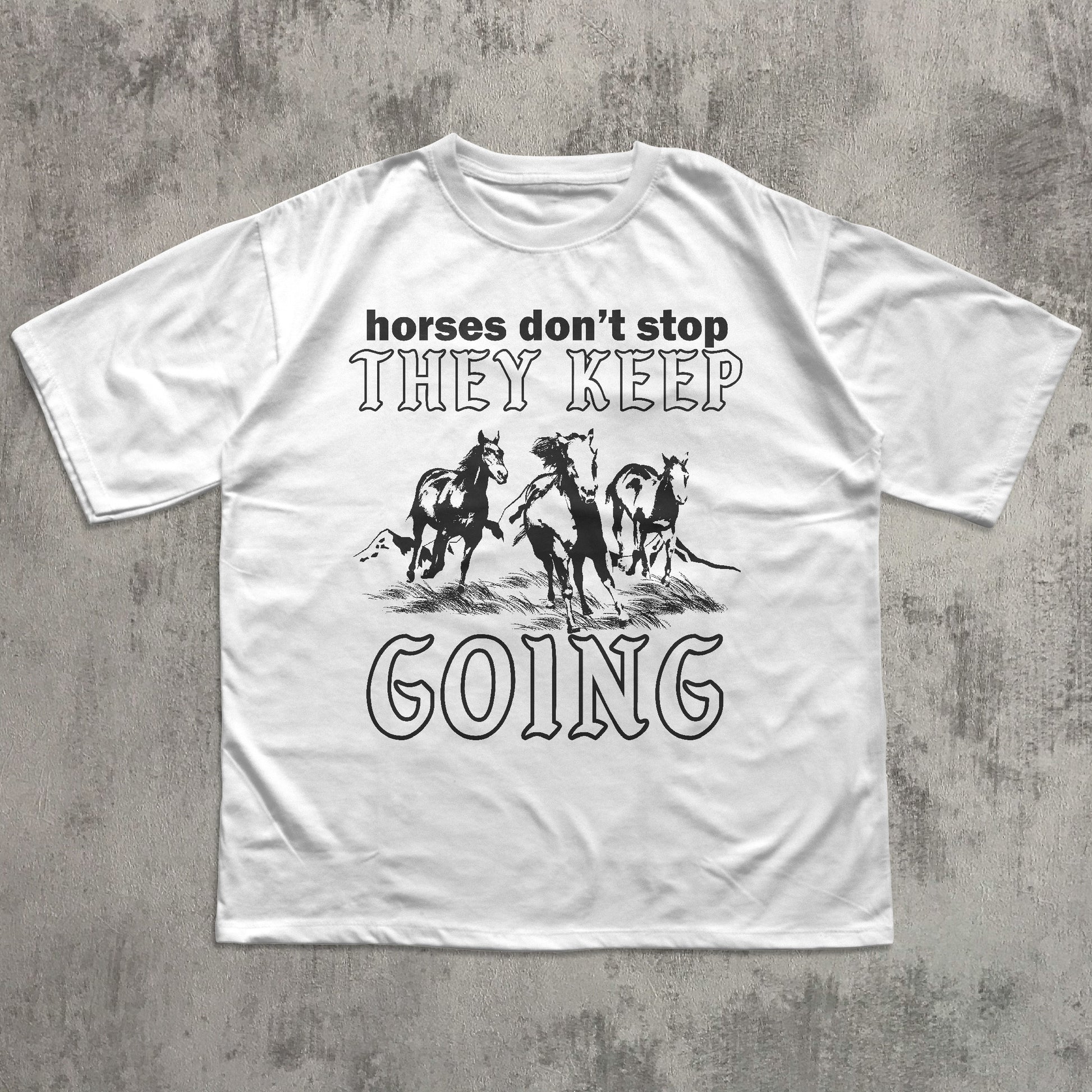 White t-shirt with graphic horse design and text on a textured gray background
